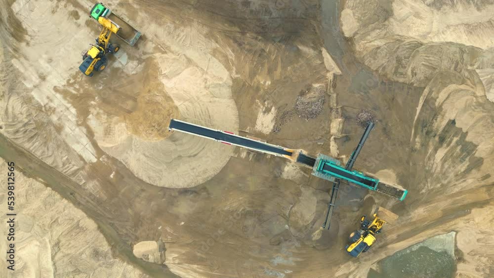 Wheel loader load sand in dump truck in open pit. Heavy machinery on developing opencast. Front end loader on earthworks in quarry. Mining truck sand transportation from open-pit mining, drone view.