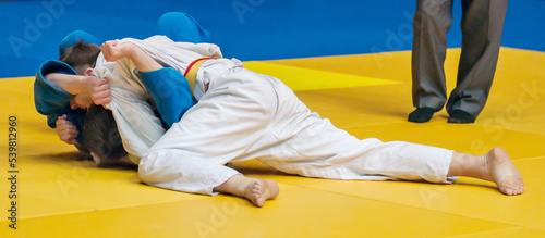 Two boys fighter judoka in judogi compete on the tatami 