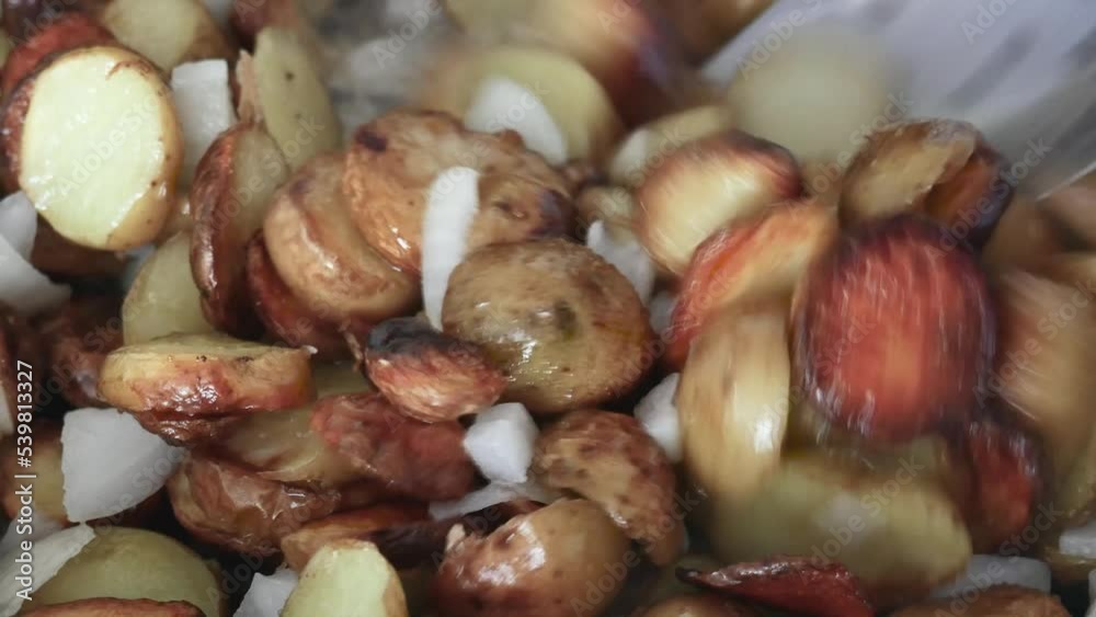 mixing with a large spoon of fried potatoes with chopped onions mixing with a large spoon of fried potatoes with chopped onions