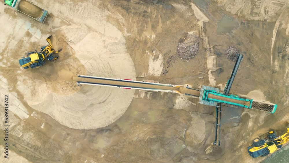 Wheel loader load sand in dump truck in open pit. Heavy machinery on developing opencast. Front end loader on earthworks in quarry. Mining truck sand transportation from open-pit mining, drone view.