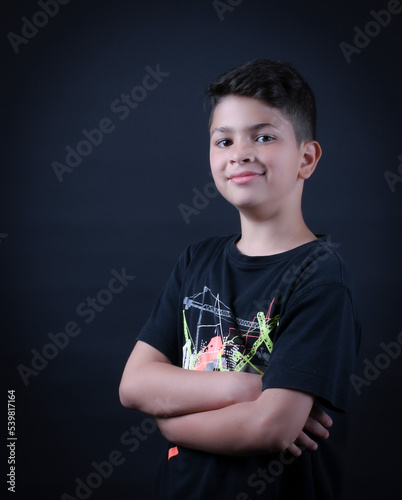 cute boy posing and smiling in a photography studio with a black T-shirt and black background 