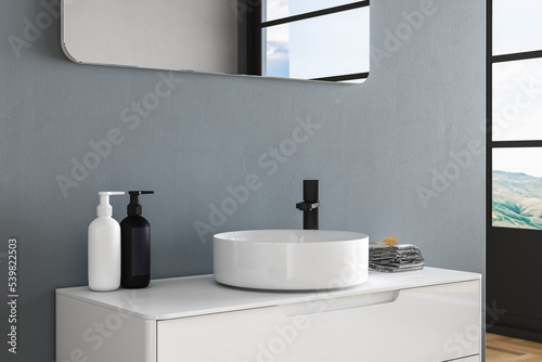 Close up of white sink with oval mirror standing in on blue wall   wooden cabinet with black faucet in minimalist bathroom. Mock up stand for display of product. 3d rendering