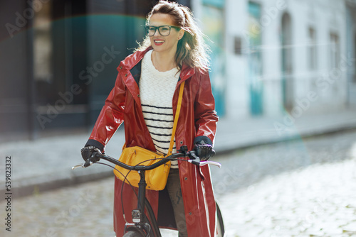 smiling stylish woman outside on city street riding bicycle