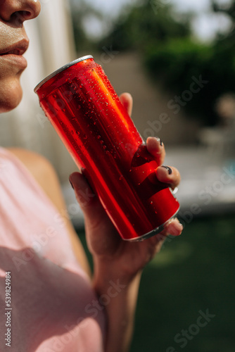 A girl on an orange background with a red tin can in her hands. Cheerful girl, advertising shooting. High quality photo
