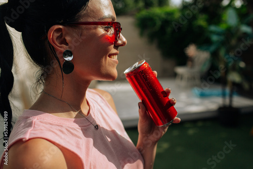 A girl on an orange background with a red tin can in her hands. Cheerful girl, advertising shooting. High quality photo