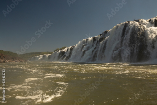 Sailing the river. The majestic Mocona waterfalls seen from the boat. The falling white water, rocks and river flowing across the jungle.