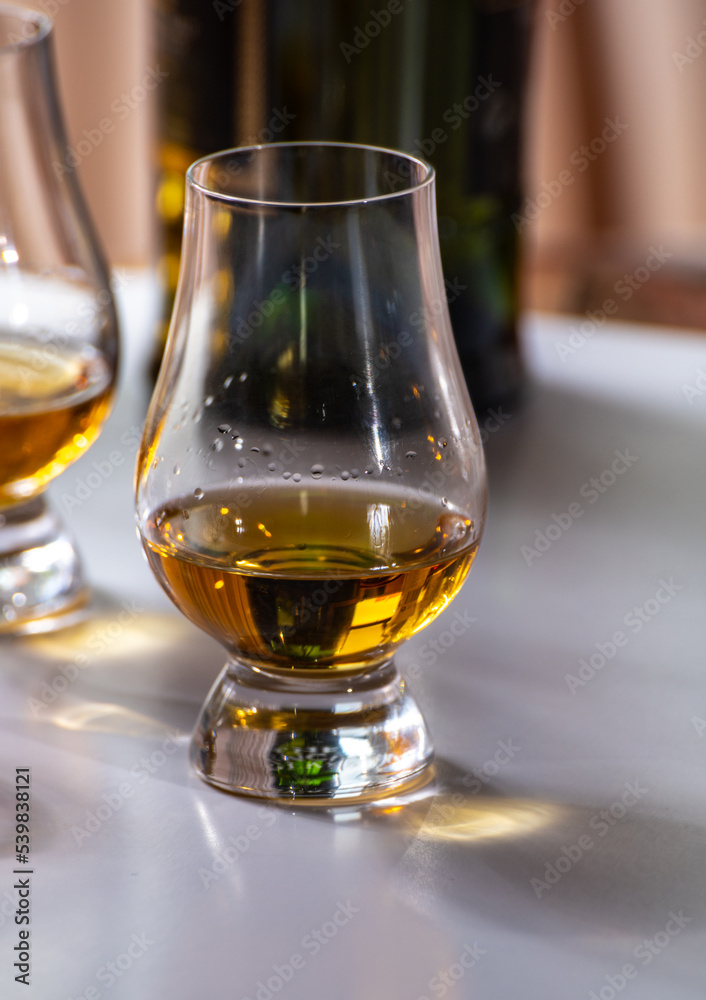 Tasting of whiskey, tulip-shaped tasting glasses with dram of Scotch single malt or blended whisky on white table Tasting of whiskey, tulip-shaped tasting glasses with dram of Scotch single malt or blended whisky on white table