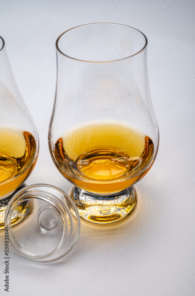 Tulip-shaped tasting glasses with dram of Scotch single malt or blended whisky on white background