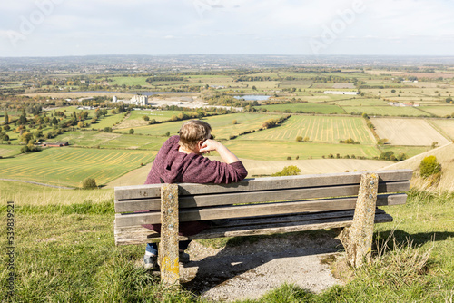 woman sitting alone on a bench overlooking a dramatic english landscape