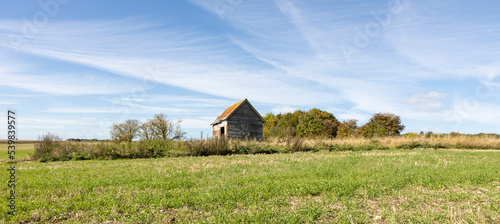 old farm building on agricultural land, open farmland blue skys