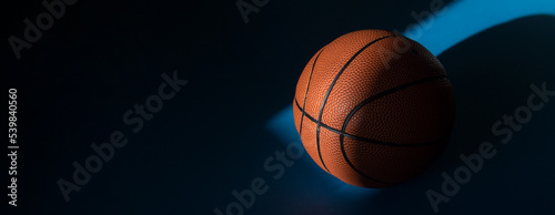 iBrown new basketball ball with natural lighting on blue background. Sport team concept. Horizontal sport theme poster, greeting cards, headers, website and app © Augustas Cetkauskas
