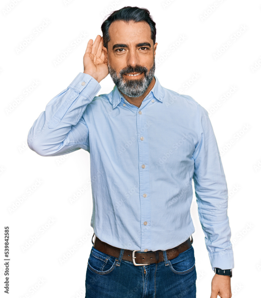 Middle aged man with beard wearing business shirt smiling with hand over ear listening an hearing to rumor or gossip. deafness concept. Middle aged man with beard wearing business shirt smiling with hand over ear listening an hearing to rumor or gossip. deafness concept.