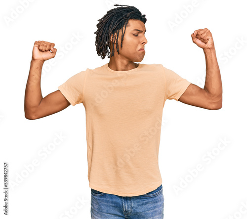 Young african american man wearing casual clothes showing arms muscles smiling proud. fitness concept.