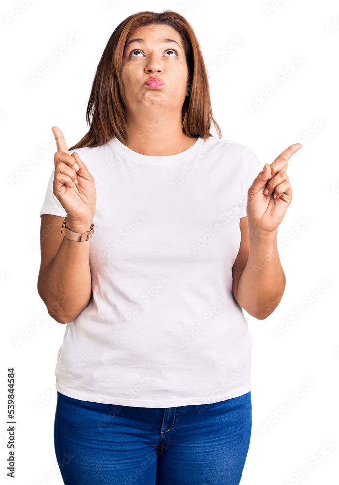 Middle age latin woman wearing casual white tshirt pointing up looking sad and upset, indicating direction with fingers, unhappy and depressed. Middle age latin woman wearing casual white tshirt pointing up looking sad and upset, indicating direction with fingers, unhappy and depressed.