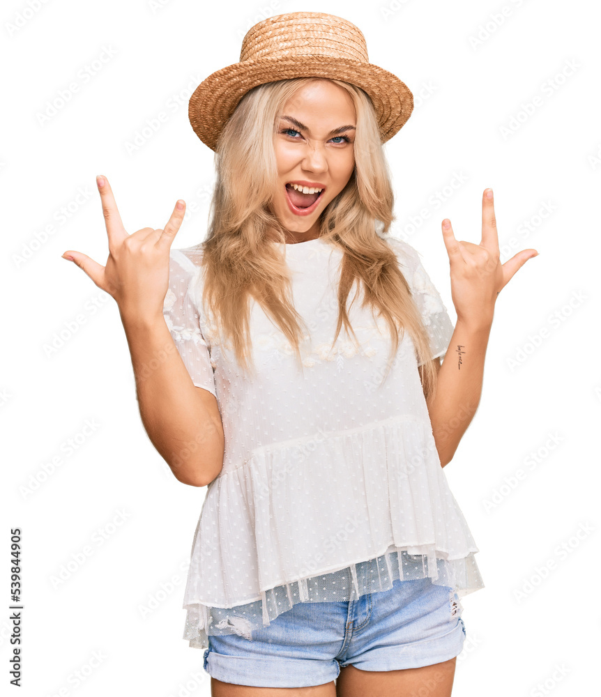 Young blonde girl wearing summer hat shouting with crazy expression doing rock symbol with hands up. music star. heavy concept. Young blonde girl wearing summer hat shouting with crazy expression doing rock symbol with hands up. music star. heavy concept.