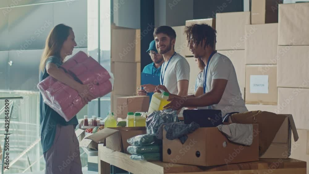 The Concept of Giving:Positive Group of Young Adult Volunteers Serving Humanitarian Aid to Refugees and Immigrants. Humanitarian Aid Charity Workers Serve Meals and Hygiene Products to People in Need. The Concept of Giving:Positive Group of Young Adult Volunteers Serving Humanitarian Aid to Refugees and Immigrants. Humanitarian Aid Charity Workers Serve Meals and Hygiene Products to People in Need.