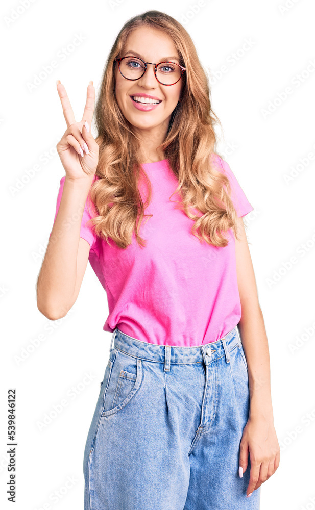 Young beautiful caucasian woman with blond hair wearing casual clothes and glasses showing and pointing up with fingers number two while smiling confident and happy.