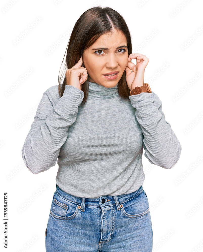 Young beautiful woman wearing casual turtleneck sweater covering ears with fingers with annoyed expression for the noise of loud music. deaf concept. Young beautiful woman wearing casual turtleneck sweater covering ears with fingers with annoyed expression for the noise of loud music. deaf concept.