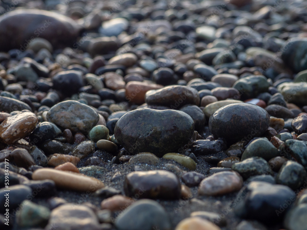 Pebbles on the seashore close-up. Rocky beach. Stones close-up with bokeh. Gray natural background. Waves and wet pebbles Pebbles on the seashore close-up. Rocky beach. Stones close-up with bokeh. Gray natural background. Waves and wet pebbles