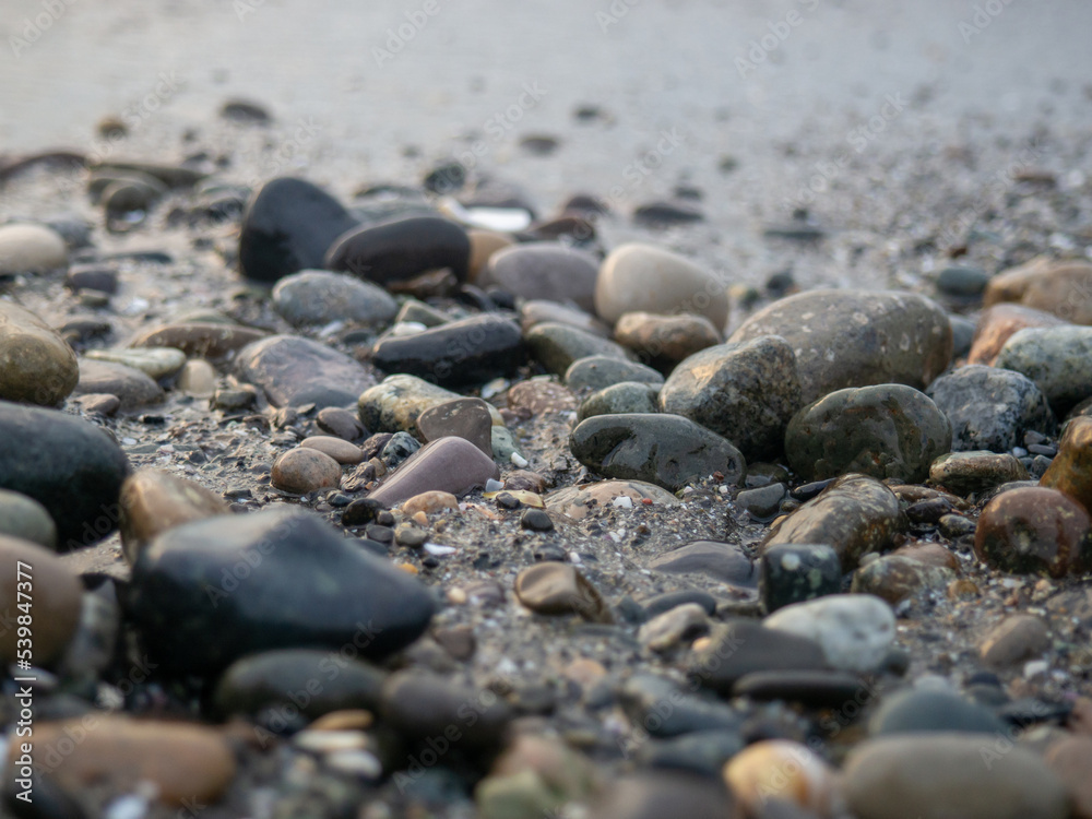 Pebbles on the seashore close-up. Rocky beach. Stones close-up with bokeh. Gray natural background. The concept of rest on the seashore. The Velvet season. Waves and wet pebbles Pebbles on the seashore close-up. Rocky beach. Stones close-up with bokeh. Gray natural background. The concept of rest on the seashore. The Velvet season. Waves and wet pebbles