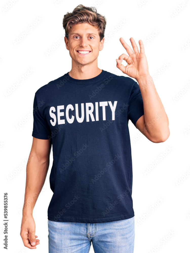 Young handsome man wearing security t shirt smiling positive doing ok sign with hand and fingers. successful expression. Young handsome man wearing security t shirt smiling positive doing ok sign with hand and fingers. successful expression.