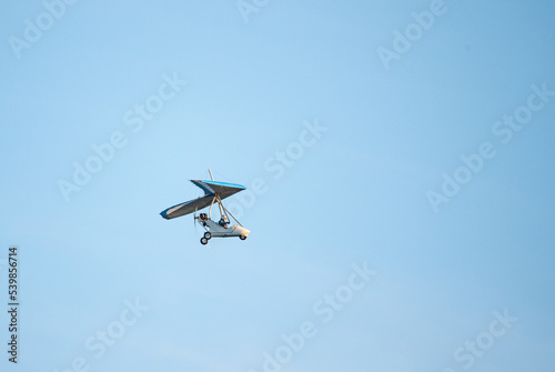 Fototapeta Naklejka Na Ścianę i Meble -  Powered paraglider flight. Hobbies and aviation sports. Paraglider against the blue sky.
