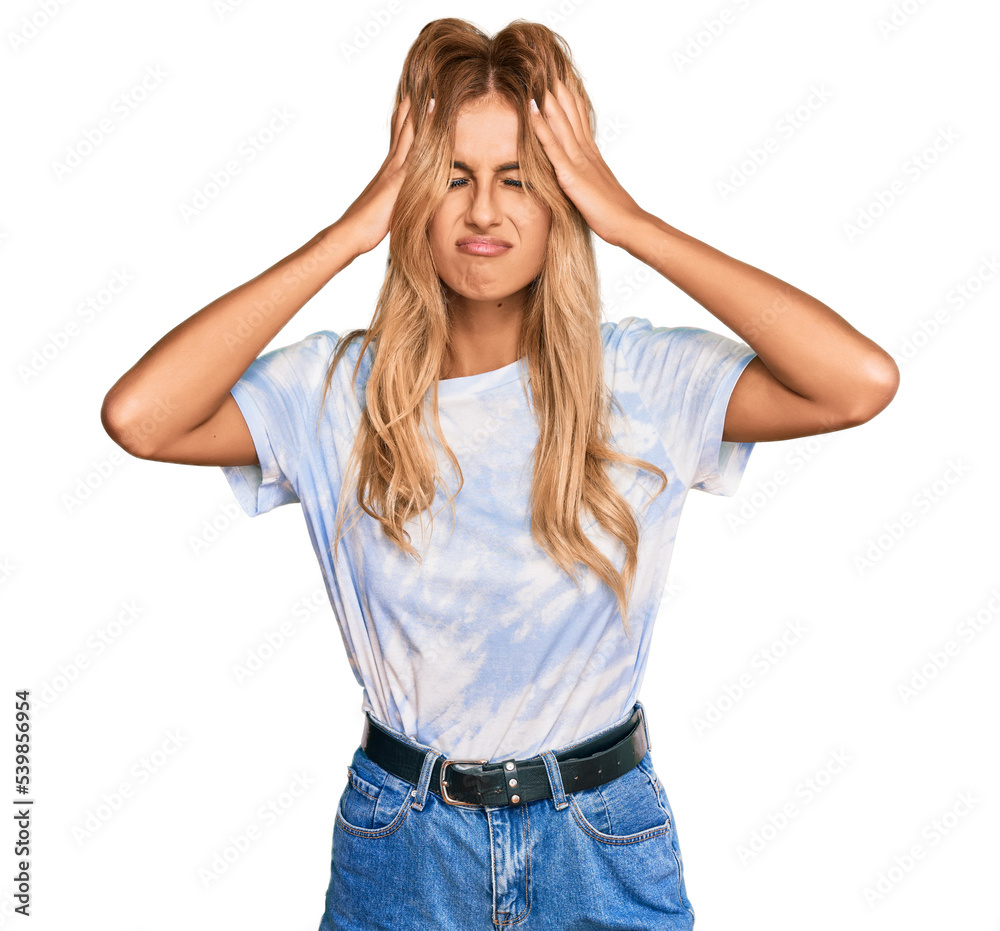 Beautiful blonde young woman wearing casual tie dye shirt suffering from headache desperate and stressed because pain and migraine. hands on head. Beautiful blonde young woman wearing casual tie dye shirt suffering from headache desperate and stressed because pain and migraine. hands on head.