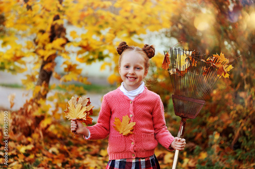 Close-up portrait of a smiling girl collecting autumn leafs