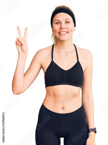 Young beautiful blonde woman wearing sportswear showing and pointing up with fingers number two while smiling confident and happy.