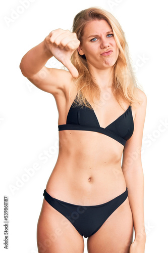 Young beautiful blonde woman wearing bikini looking unhappy and angry showing rejection and negative with thumbs down gesture. bad expression.