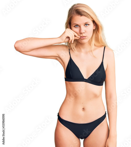 Young beautiful blonde woman wearing bikini mouth and lips shut as zip with fingers. secret and silent, taboo talking