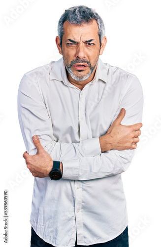 Middle age hispanic with grey hair wearing casual white shirt shaking and freezing for winter cold with sad and shock expression on face © Krakenimages.com