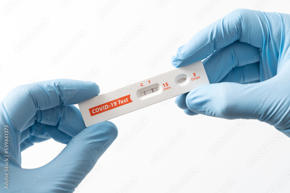 Naklejka premium Hand is showing positive results on rapid antigen test kit for covid-19.