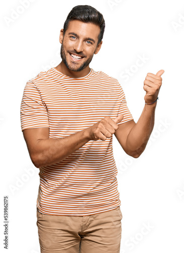 Handsome hispanic man wearing casual clothes pointing to the back behind with hand and thumbs up, smiling confident