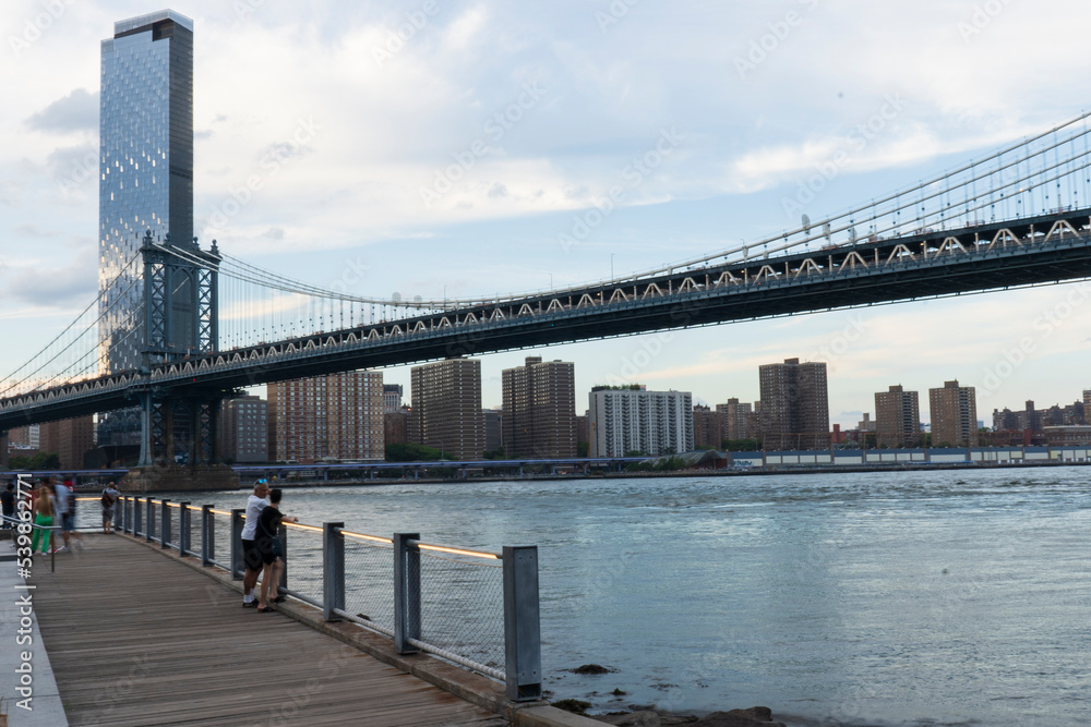 Fototapeta premium Empire Fulton Ferry promenade area in Brooklyn Bridge Park. Located between the historic Manhattan and Brooklyn Bridges. Seen here is the Manhattan Bridge.