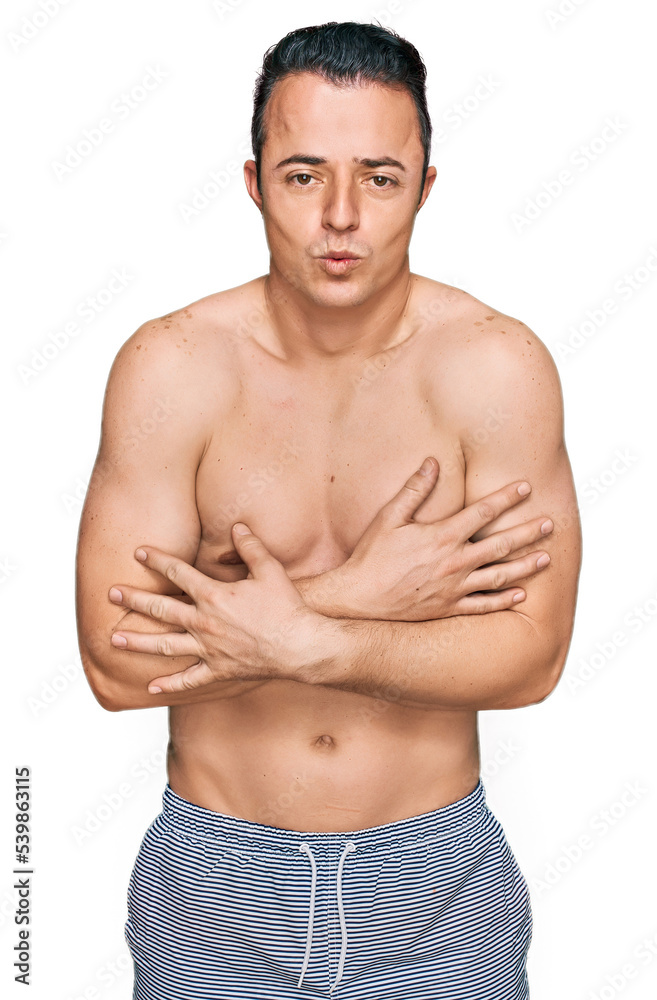 Fototapeta premium Handsome young man wearing swimwear shirtless shaking and freezing for winter cold with sad and shock expression on face