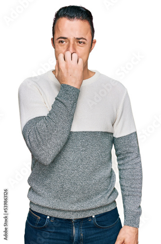 Handsome young man wearing casual winter sweater looking stressed and nervous with hands on mouth biting nails. anxiety problem.