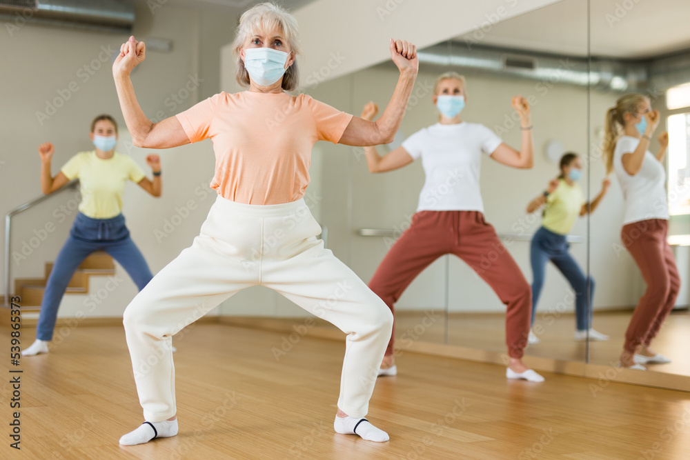 Family in protective masks are engaged in sports dancing in the gym