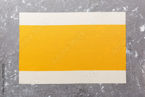 Top view of yellow tablecloth for food on cement background. Empty space for your design.
