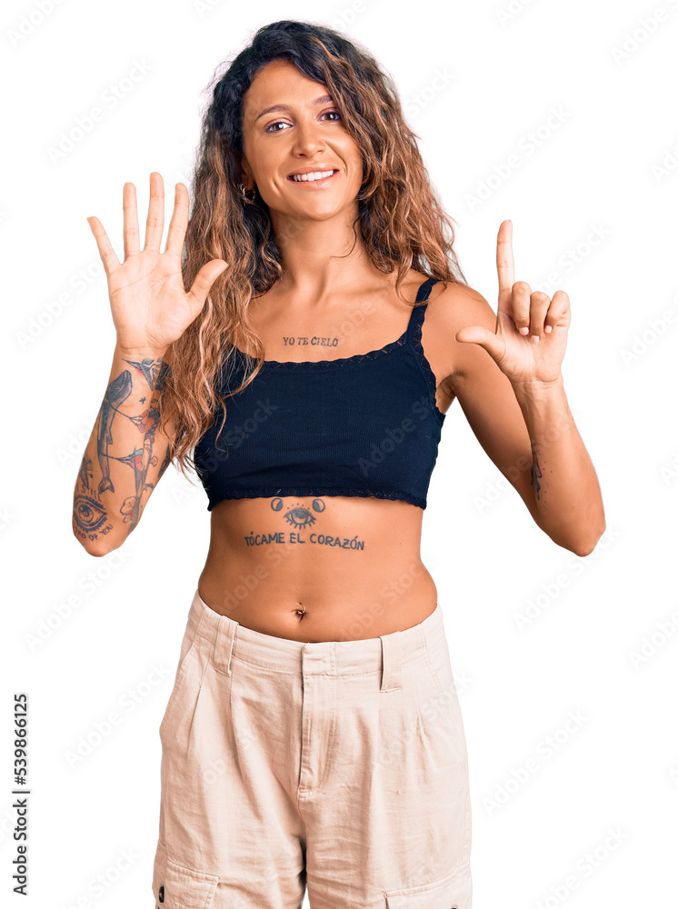 Young hispanic woman with tattoo wearing casual clothes showing and pointing up with fingers number seven while smiling confident and happy. Young hispanic woman with tattoo wearing casual clothes showing and pointing up with fingers number seven while smiling confident and happy.