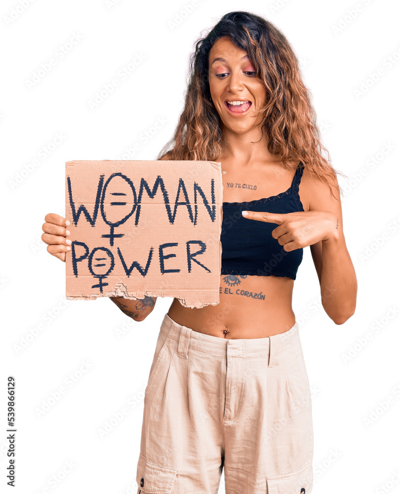Young hispanic woman with tattoo holding woman power banner smiling happy pointing with hand and finger