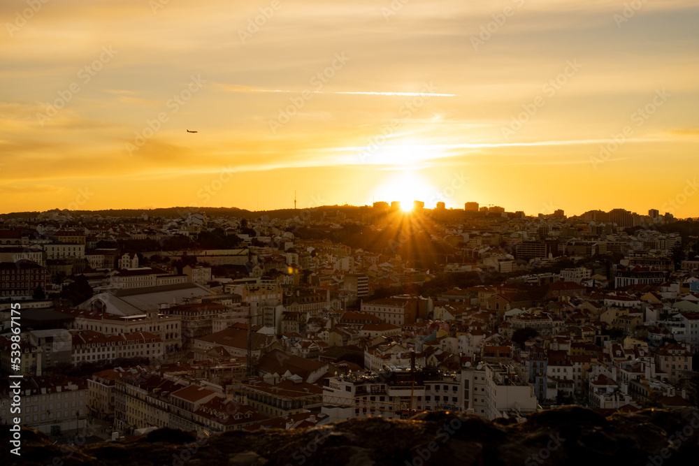Lisbon city old town landscape during sunset. Golden hour in Lisbon with a view of red rooftops, blue sky and the April 25 Bridge in a distance, view of Lisbon from São Jorge Castle
