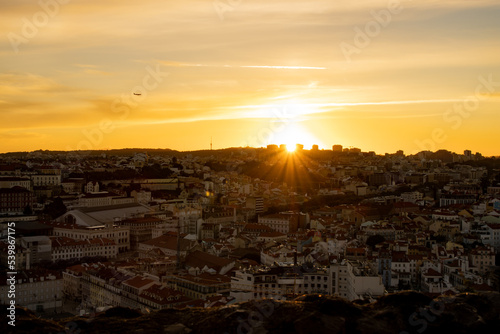 Lisbon city old town landscape during sunset. Golden hour in Lisbon with a view of red rooftops, blue sky and the April 25 Bridge in a distance, view of Lisbon from São Jorge Castle