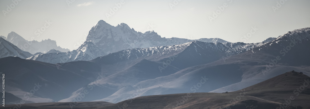 Mountain rocky ranges of the Caucasus with snow and glaciers, panorama on a sunny summer morning