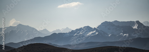 Monochrome panorama of the mountain snow-capped peaks of the Caucasus with snow and glaciers in side lighting, on a sunny summer morning © Denis