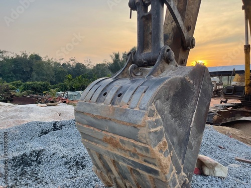 Backhoe working at a construction site. Tracked excavator loading of stone on ground earth with sky background