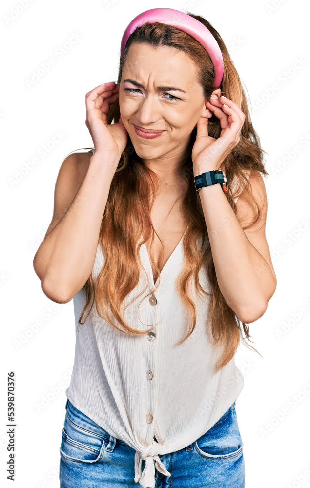 Young caucasian woman wearing casual style with sleeveless shirt covering ears with fingers with annoyed expression for the noise of loud music. deaf concept. Young caucasian woman wearing casual style with sleeveless shirt covering ears with fingers with annoyed expression for the noise of loud music. deaf concept.