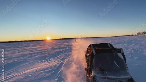 View from the snowmobile at speed. Large snowy field in winter. Evening sunset in Siberia. Red sun at sunset photo