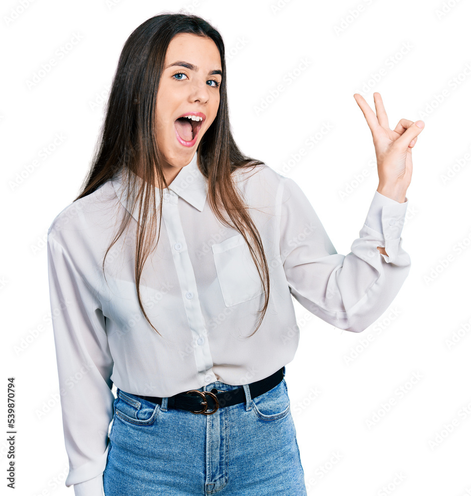 Young brunette teenager wearing business white shirt smiling with happy face winking at the camera doing victory sign. number two. Young brunette teenager wearing business white shirt smiling with happy face winking at the camera doing victory sign. number two.
