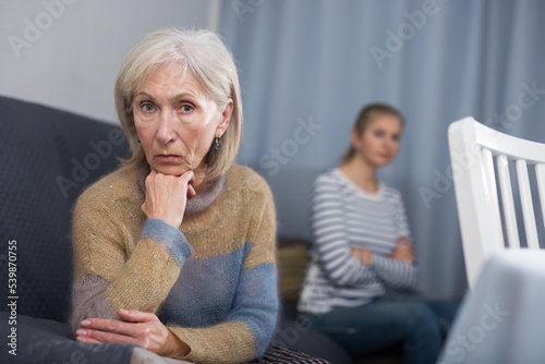 Quadro su tela Elderly mother and adult daughter sit on the couch turned away from each other a